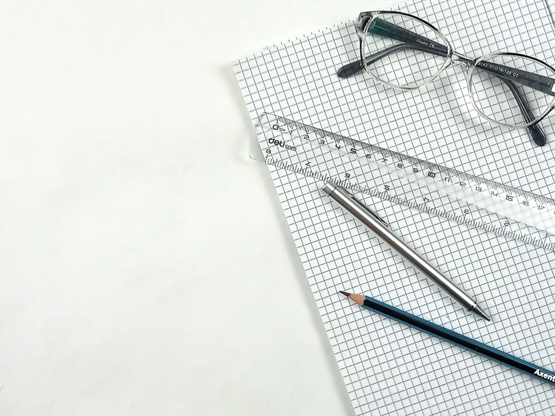 A clean, minimal shot of architectural blueprints or property survey plans on a desk, with a pair of glasses and a pen resting on top, signifying the detailed review of a home's title and survey.