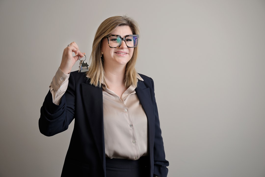 A professional real estate agent smiles while handing a set of modern house keys to a happy couple, representing a successful and smooth home purchase.